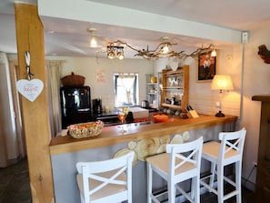 A kitchen with a central island, bar stools, a coffee machine, and a decorative ceiling light.
