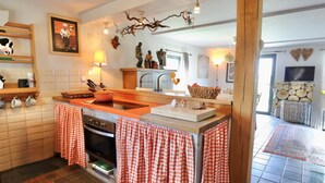 A kitchen with a checkered tablecloth, a stove, and a television.