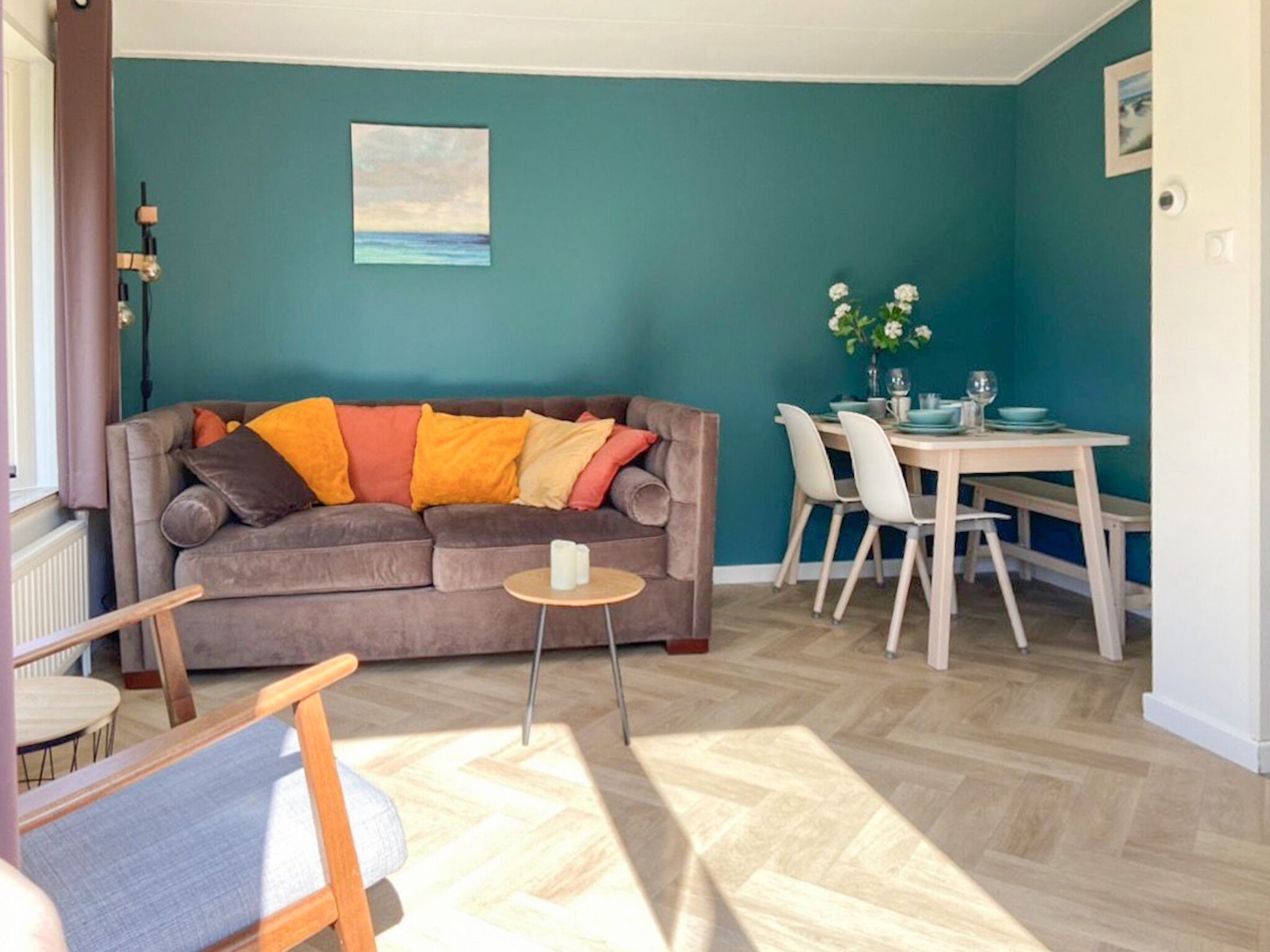 A living room with a sofa, a small round table, and a dining area with chairs and a table.