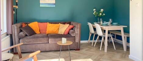 A living room with a sofa, a small round table, and a dining area with chairs and a table.