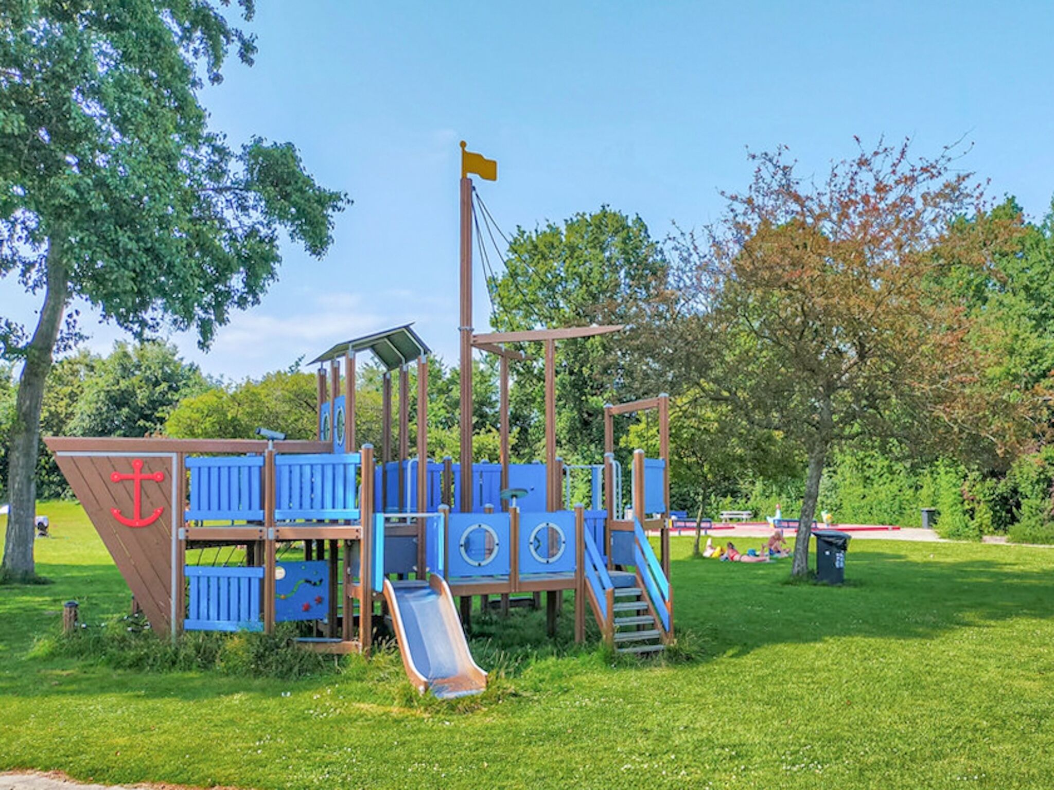 A playground with a slide, climbing structures, and a flag.