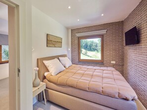 Een slaapkamer met een bed, een raam, een schilderij en een bakstenen muur.