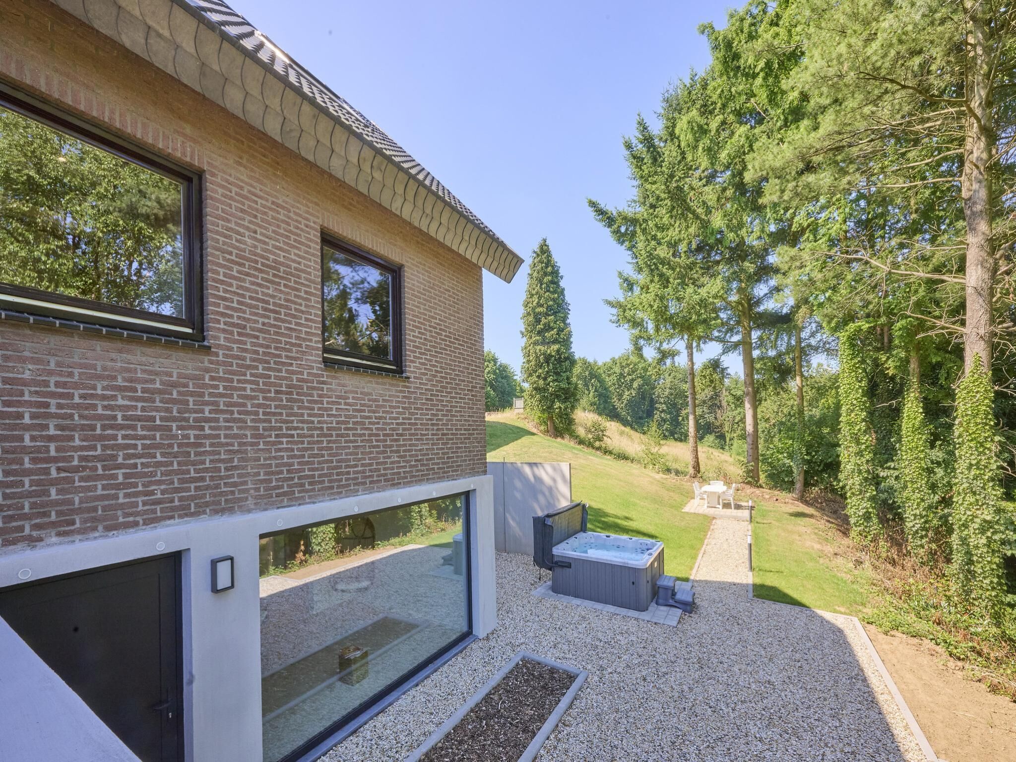 Een modern huis met een bakstenen gevel, grote ramen en een patio met een jacuzzi.
