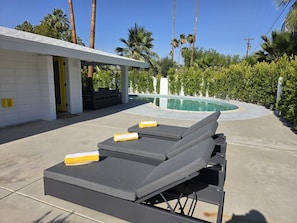 Ein Poolbereich mit Liegestühlen, einer überdachten Terrasse und einem Schwimmbecken.