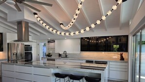 Une cuisine moderne dotée d’un îlot central, de tabourets de bar et de luminaires suspendus.