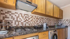 Uma cozinha equipada com fogão a gás, micro-ondas, máquina de café e máquina de lavar.
