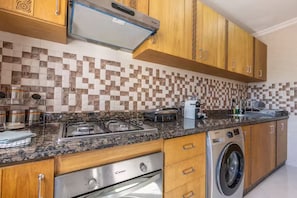 A kitchen with a gas stove, a microwave, a coffee maker, and a washing machine. - Splendid bright 2BR apartment in central Tangier (Tangier)