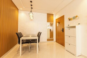 Uma sala de jantar moderna com uma mesa redonda, cadeiras, uma luminária pendente, uma porta de madeira e um armário branco.