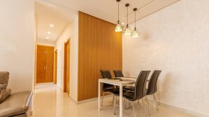 Uma sala de jantar moderna com um painel de madeira decorativo, uma mesa branca e cadeiras pretas.