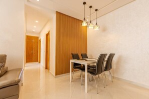 A modern dining area with a wooden accent wall, a white table, and black chairs. - Splendid bright 2BR apartment in central Tangier (Tangier)