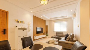 Uma sala de estar moderna com área de jantar, sofá e televisão na parede.