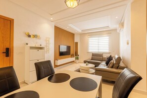 A modern living room with a dining area, a sofa, and a TV mounted on the wall. - Splendid bright 2BR apartment in central Tangier (Tangier)