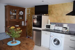 Eine kompakte Küche mit Mikrowelle, Toaster, Kaffeemaschine, Geschirrspüler und Backofen.