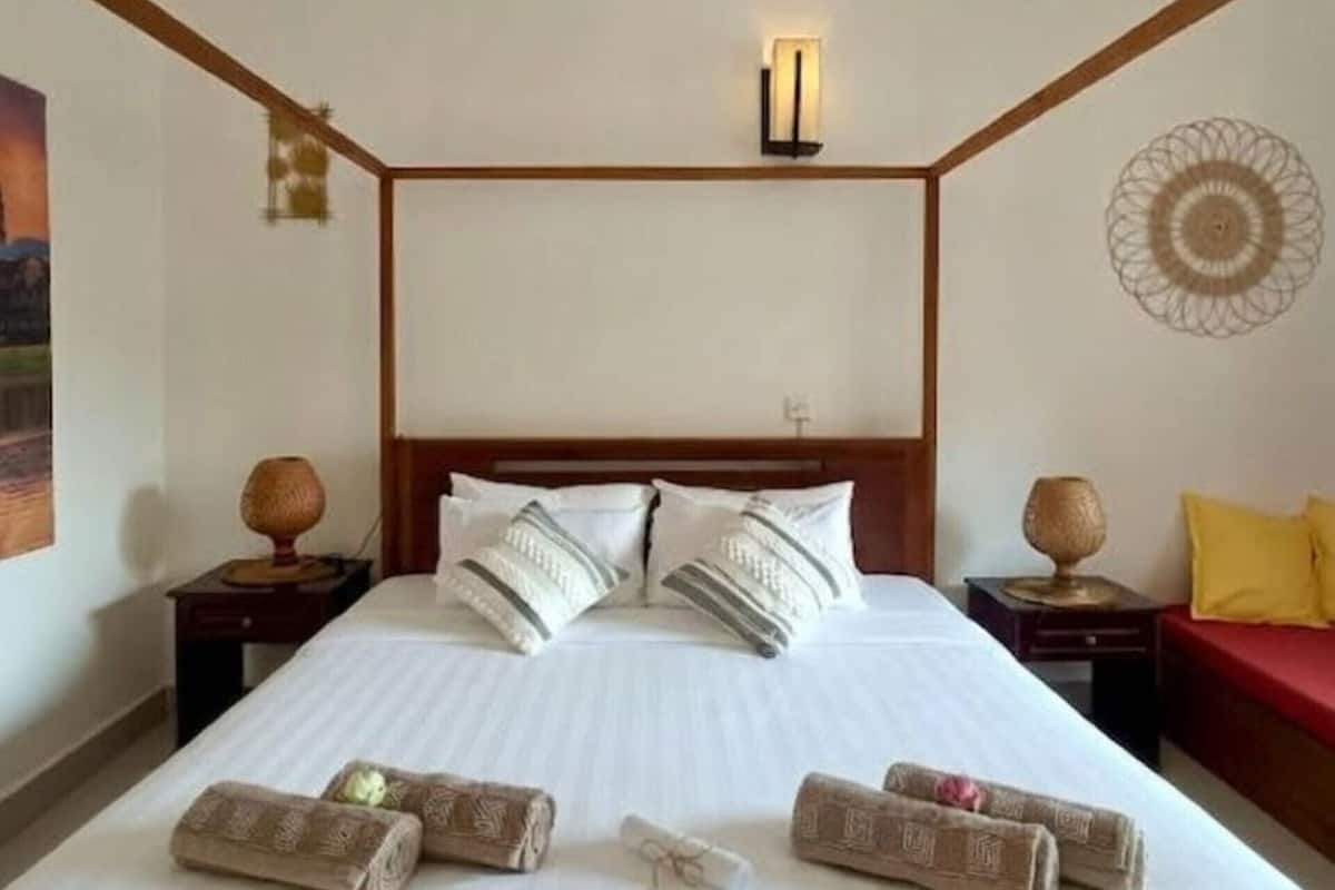 Ein Hotelzimmer mit einem großen Bett, einem Holzkopfstück, zwei Nachttischen, einer Wandleuchte und einem Wanddekor.