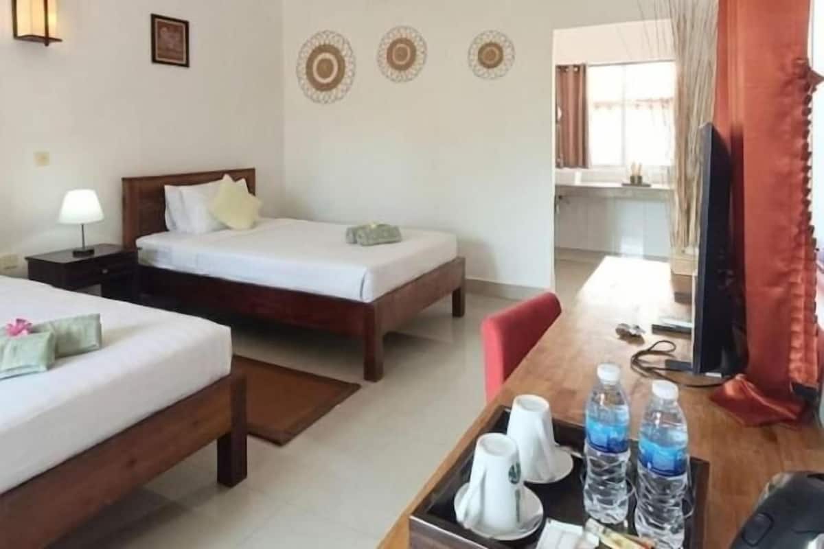 Ein Hotelzimmer mit zwei Betten, einem Schreibtisch, einem Computer, einer Lampe und einem Fernseher.