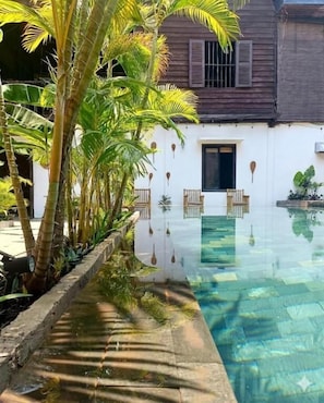 A clear swimming pool with a wooden deck and tropical plants. - La Fontaine de Tara Boutique Hotel (Siem Reap)