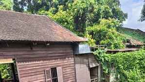 A wooden building with a tiled roof, surrounded by lush greenery and a small outdoor seating area with wicker furniture. - La Fontaine de Tara Boutique Hotel (Siem Reap)