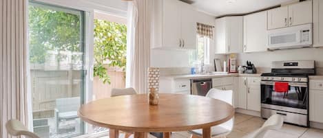 A modern kitchen with white cabinets, a round wooden table, and a dining area with chairs.