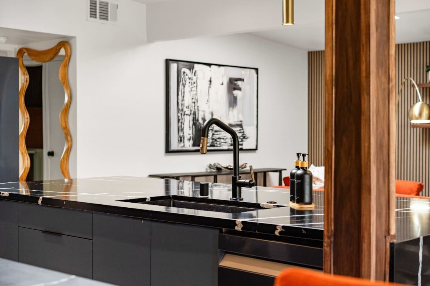 Una cocina moderna con encimera negra, grifo negro y armario de madera.