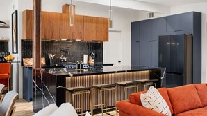 A modern kitchen with a central island, dark cabinetry, and a sleek refrigerator.