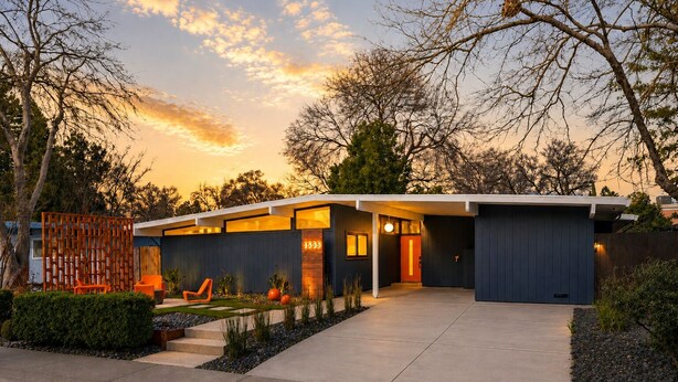 A modern house with a driveway, a wooden fence, and a well-maintained garden.