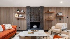A modern living room with a fireplace, a sofa, a coffee table, and decorative shelves. - Midcentury Modern Oasis: Atomic Ranch Reimagined (Davis)