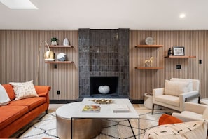 A modern living room with a fireplace, a sofa, a coffee table, and decorative shelves.