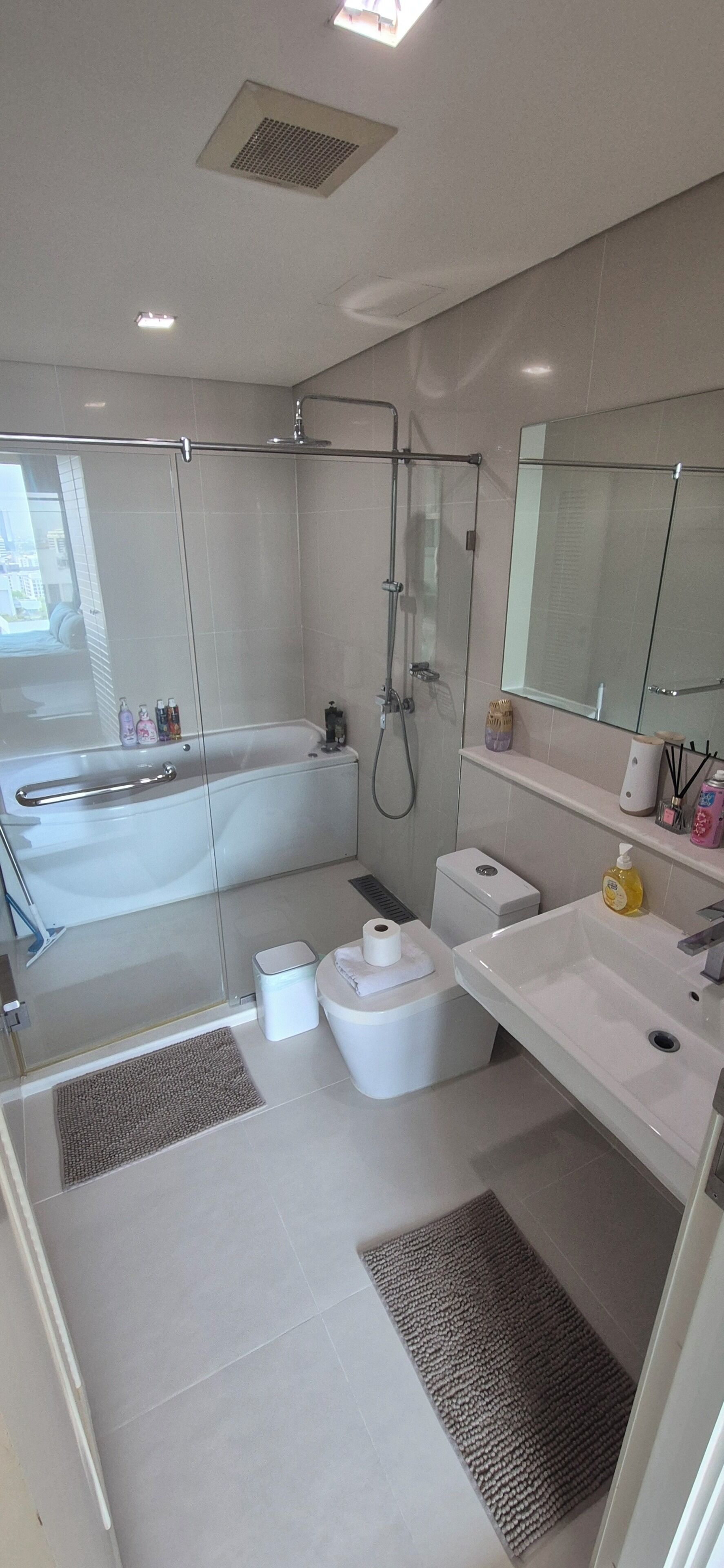 Une salle de bain moderne avec une douche à parois de verre, une baignoire blanche, des toilettes et un lavabo avec un miroir au-dessus.