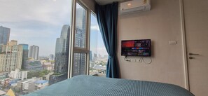 Ein Hotelzimmer mit großem Fenster, einem Wand-Fernseher und einer Tür.