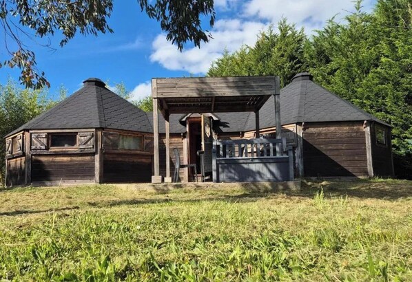 Eine rustikale Holzhütte mit einer Holzveranda, einem kleinen Anbau und einem geneigten Dach.