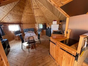 Eine Hütte mit Schlafzimmer im oberen Bereich, Essbereich und Küchenzeile.