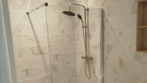 Une salle de bain moderne avec une douche à parois de verre, un meuble-lavabo en bois et des carreaux de marbre.