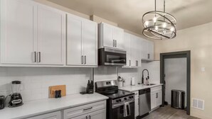 A modern kitchen with white cabinets, stainless steel appliances, and a central island. - Chic 2bd/Free parking/Nr Arpt/Nr Downtown/Firepit (St. Louis)