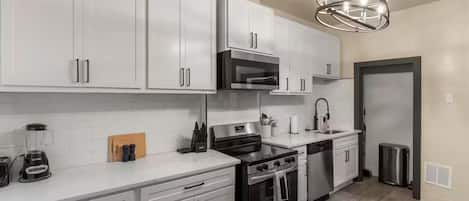 A modern kitchen with white cabinets, stainless steel appliances, and a central island.