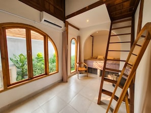 A room with a bed, a chair, a ladder, and large windows with a view of greenery. - 3-bedroom family house with pool, garden and toys (Kuta Selatan)