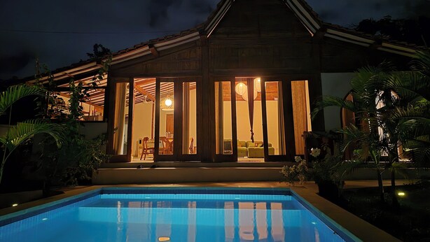 Una casa con piscina, fachada de madera y ventanas amplias.