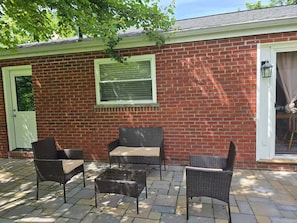 A patio area with wicker furniture, a brick wall, and a window.