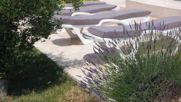A patio with lounge chairs, a covered seating area, and potted plants. - Couples getaway with pool and pool house (Arles)