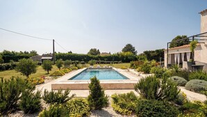 A rectangular swimming pool surrounded by landscaped garden beds and various shrubs. - Couples getaway with pool and pool house (Arles)