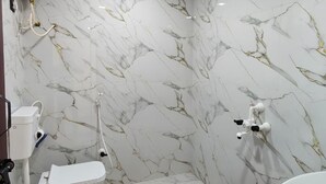 A bathroom with a toilet, bidet, sink, and a small stool.