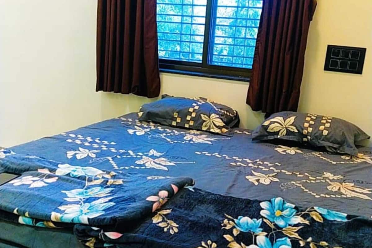 A bedroom with a bed, curtains, a window, and a wall switch.