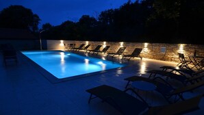 Una piscina con sillas de descanso y un muro de piedra.