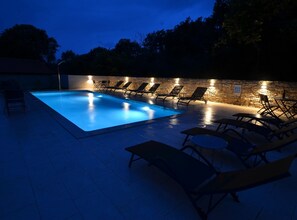 A swimming pool with lounge chairs and a stone wall. - Tranquil Getaway With Shared Pool in Bale - One Bedroom Apartment (Bale)