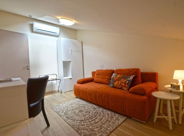 A compact living space with a sofa, a small table, a chair, and a rug. - Tranquil Getaway With Shared Pool in Bale - One Bedroom Apartment (Bale)