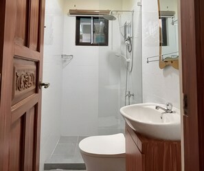 Un bany amb vàter, rentamig, dutxa i un mirall.