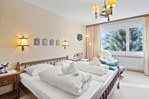 Une chambre d’hôtel avec deux lits, des lampes de chevet, une fenêtre avec des rideaux et une vue sur des arbres couverts de neige.