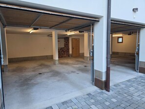 En parkeringskælder med beton gulve, metal søjler og åbne garageporte.