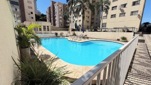 A swimming pool with a white fence, surrounded by potted plants and lounge chairs. - 5 Estrelas - Alto do Bueno (Goiânia)