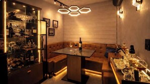 A modern bar area with a glass table, cushioned seating, and a wine rack. - 5 Estrelas - Alto do Bueno (Goiânia)