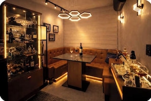A modern bar area with a glass table, cushioned seating, and a wine rack. - 5 Estrelas - Alto do Bueno (Goiânia)